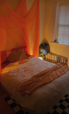 a bed with an orange canopy over it in a bedroom next to a book shelf