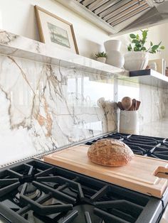 a loaf of bread sitting on top of a wooden cutting board next to a stove