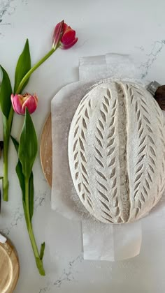 a white cake sitting on top of a table next to flowers