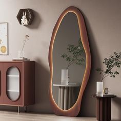 an oval shaped mirror on the wall next to a side table with a plant in it