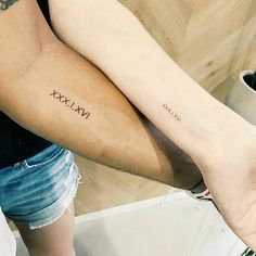 two people with matching tattoos on their arms, one is holding the other's arm