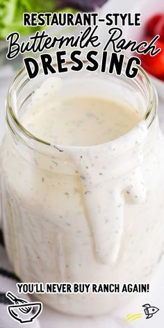 a glass jar filled with dressing sitting on top of a white counter next to vegetables