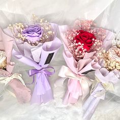 three bouquets of flowers are wrapped in pink and purple paper with ribbons around them