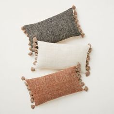 three pillows with tassels on them sitting side by side in front of the words west elm