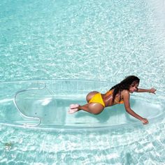 a woman in yellow swimsuit floating on clear blue water with her legs spread out