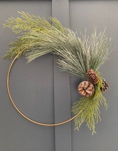 a wreath with pine cones and greenery hangs on a door handle, decorated with gold wire