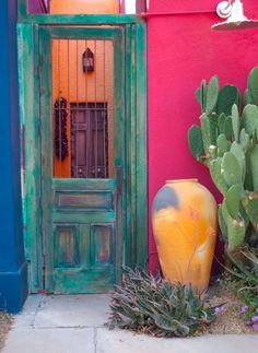 an old door is painted bright pink, green and yellow in front of a cactus plant