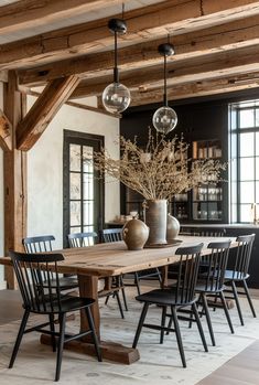 a dining room table with chairs and vases on it