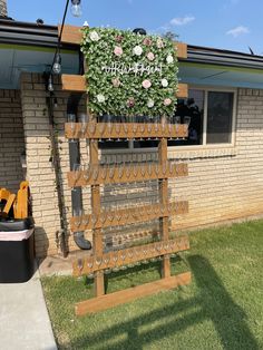 a wooden rack with flowers and gardening tools on it in front of a brick building