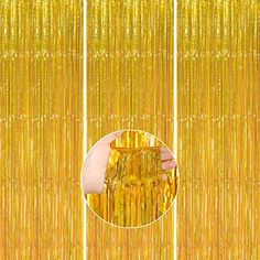 a hand is touching the side of a gold curtain