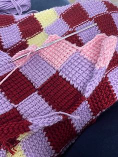 a crocheted blanket is being worked on with scissors