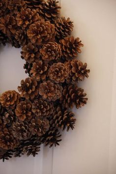 a wreath made out of pine cones hanging on a door