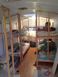 two people are sitting on bunk beds in the back of a van with wood flooring