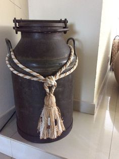 a large black vase sitting on top of a white counter next to a wall with a rope hanging from it