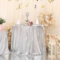 two silver sequin tablecloths on top of a round table with white flowers