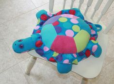 a blue turtle pillow sitting on top of a white chair with polka dot fabric covering