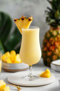 a pineapple drink is garnished with a piece of fruit on the side