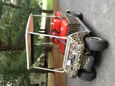 a leopard print golf cart parked in a parking lot next to trees and a house