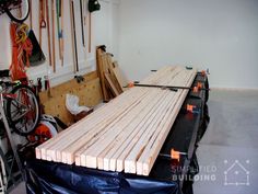 a garage with lots of wooden boards on the floor and bikes hanging from the wall