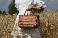 a woman holding a wicker basket in a wheat field