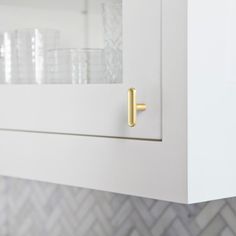 a close up of a kitchen cabinet door with glass and brass handles on the doors