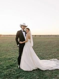 a bride and groom pose for a photo in the middle of an open field at sunset