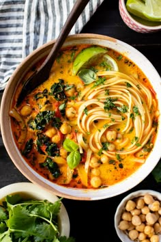 a bowl of soup with noodles, spinach and chickpeas on the side