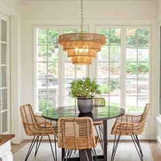 a dining room table with wicker chairs and a potted plant in the center