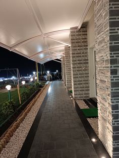 an empty walkway between two buildings at night with lights shining on the building's side