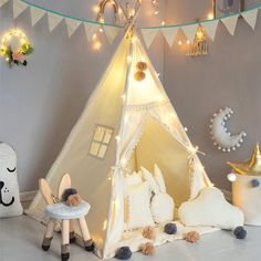 a child's teepee tent with lights on it and stuffed animals in front