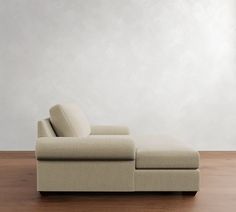 a couch sitting on top of a wooden floor next to a white wall and wood floor