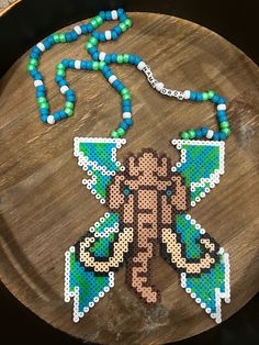 Dubstep artists Excision x Wooli perler necklace. Shown in green and blue color way and pink and purple but can be customized! Bass Canyon Perler, Perler Beads Ideas Rave, Green Spacer Beads For Crafting, Green Necklace With Letter Beads For Gift, Unique Green Beads For Crafting, Handmade Green Beads For Crafting, Excision Perler Pattern, Sullivan King Perler, Lost Lands Perler