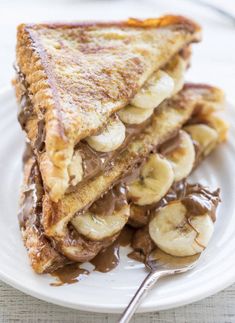 grilled french toast with nutella and chocolate sauce on top, stacked high on a white plate