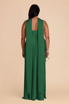 a woman in a green dress with her back turned to the camera, looking down