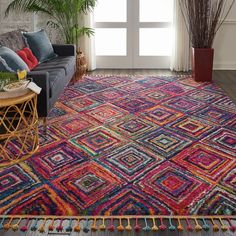 a living room area with a couch, rug and potted plant on the floor