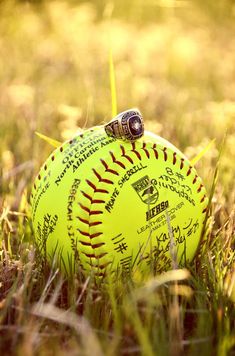 a yellow baseball sitting on top of a lush green field