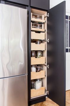 an organized pantry in the middle of a kitchen with stainless steel refrigerator and wooden flooring