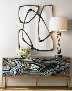 an art deco sideboard with marble and gold accents in the living room, next to a large mirror