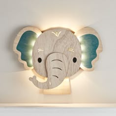 a wooden elephant head mounted to the wall with lights on it's face and ears