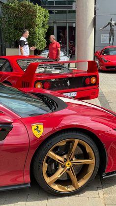 ferrari cars parked in front of a building with people looking at them on the sidewalk