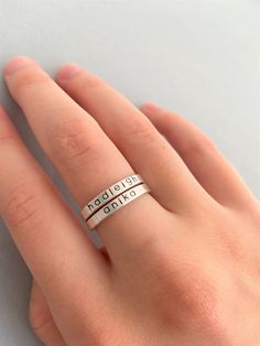 The Slender Name Ring is a personalized sterling silver ring stamped with your choice of names or dates. I make these in a 2mm sterling silver wire with rounded edges and hand stamped in lower block letters. This ring is made in the same wire as my Hammered Stacking Name Rings, but I offer this with a smooth texture and the lower block font. The smooth surface makes the letters a bit easier to read. These rings are great for stacking! I've shown pics of them stacked with my heart and star accent Adjustable Stamped Stackable Rings For Everyday, Simple Personalized Adjustable Rings, Simple Adjustable Personalized Rings, Simple Adjustable Personalized Ring, Personalized Silver Stackable Rings In Minimalist Style, Personalized Silver Stackable Rings Minimalist Style, Personalized Adjustable Stackable Rings, Simple Personalized Silver Stackable Rings, Personalized Simple Silver Stackable Rings