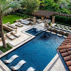 an aerial view of a pool with lounge chairs and palm trees in the foreground