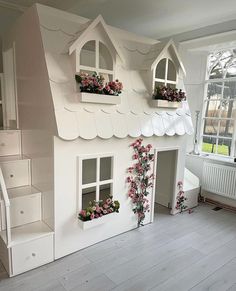 a doll house with flowers in the windows and stairs leading up to the second floor