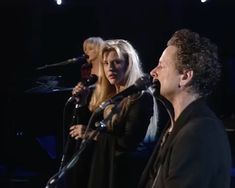 two women and a man singing into microphones