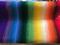 a crocheted rainbow blanket sitting on top of a bed