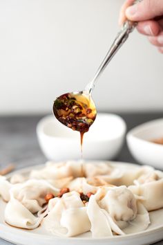 a person is dipping sauce on some dumplings