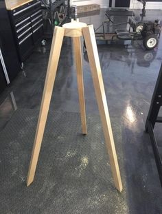 a wooden tripod stands on the floor in a garage