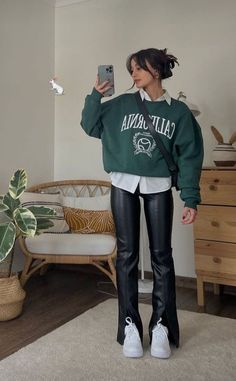 a woman wearing black leather pants and a green sweatshirt