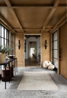 a hallway with wooden paneling and large windows next to a rug on the floor