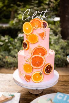 there is a pink cake with oranges on it and the words delett written in cursive writing